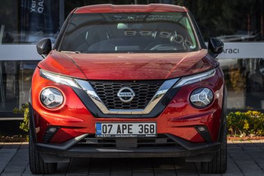 Taraf; Türkiye 18 Şubat 2023: Turuncu Nissan Juke, sıcak bir günde bir otosalonun arka planına karşı sokağa park edildi 