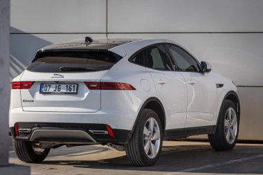 Yan, Türkiye - 18 Şubat 2023: Beyaz Jaguar E-Temposu sıcak bir günde bir otosalonun arka planına karşı sokağa park edildi 