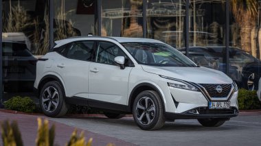 Yan, Türkiye - 18 Şubat 2023: Beyaz Nissan Kashqai, sıcak bir yaz gününde otosalona karşı sokakta park halinde. 