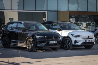 Antalya, Türkiye - 18 Şubat 2023: Otomobil bayiliğinin yanındaki yeni arabalar. Siyah Volvo XC90 ve beyaz Volvo XC40, otosalona karşı sıcak bir günde sokağa park etti 