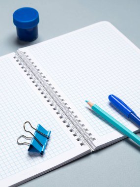 Açık bir defter, kalemler, fırçalar, suluboya ve diğer kırtasiye malzemeleriyle açık bir okul çocuğunun işyeri