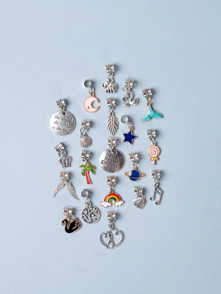 A variety of metal charms for a child\'s necklace or bracelet. Many charms isolated on a white background: planet , star,  seashell, tree,  crown , lekki, etc.