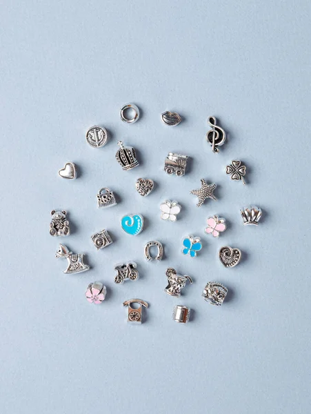 A variety of metal charms for a child's necklace or bracelet. Many charms isolated on a white background: star ,  flower,  lips, tree, cactus, lekki, etc.