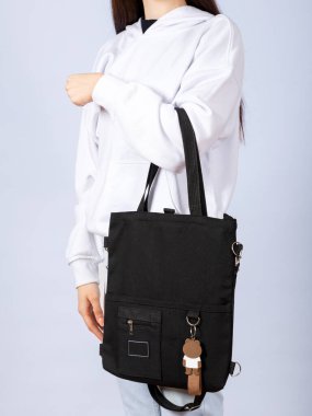 Stüdyoda beyaz bir arka planda siyah bir çevre çantası tutan bir kadın var. Metin için boş alan. Plastik kirliliğini durdur.