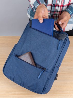 Genç bir erkek öğrencinin sırt çantasından kitap ve defter çıkarırken yakın plan fotoğrafı..