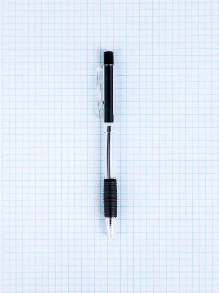 一支黑色圆珠笔的特写躺在一个格子笔记本上 准备开始工作 — 图库照片