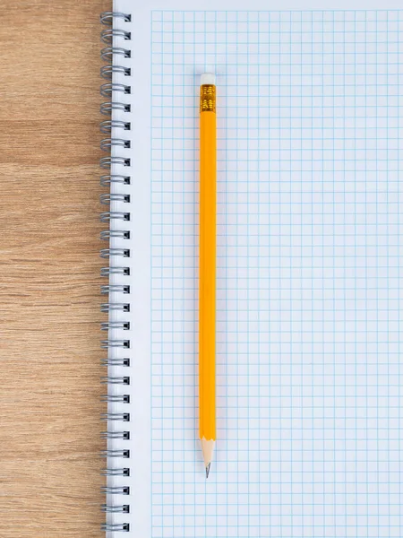 一只黄色石板铅笔的特写躺在一个格子笔记本上 准备开始工作 — 图库照片