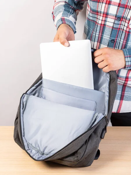 Man Puts Laptop Backpack Light Background Young Man Packs Laptop — Stock Photo, Image