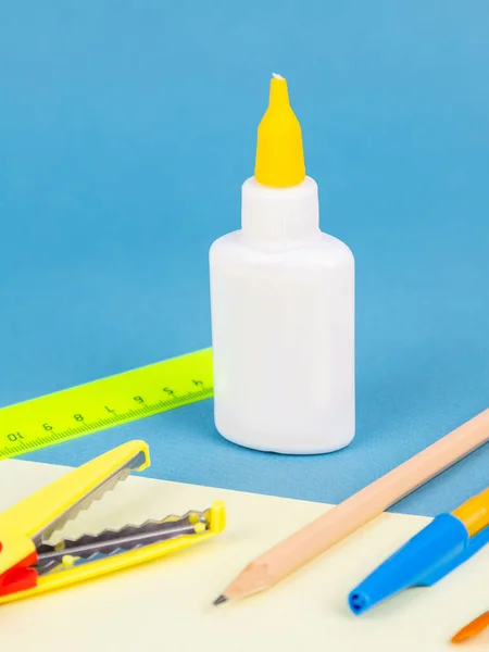 Glue Bottle Next Various Office Supplies Isolated Blue Background Closeup — Stock Photo, Image
