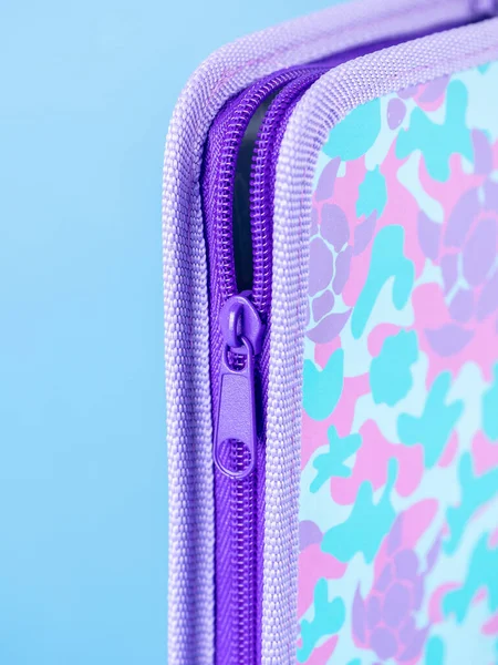 close-up of a zipper on a pink school pencil case on a blue background. Back to school. copy space