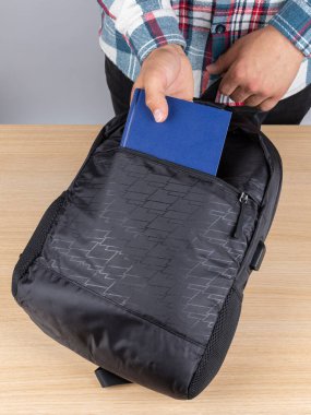 Genç bir erkek öğrencinin sırt çantasından kitap ve defter çıkarırken yakın plan fotoğrafı..