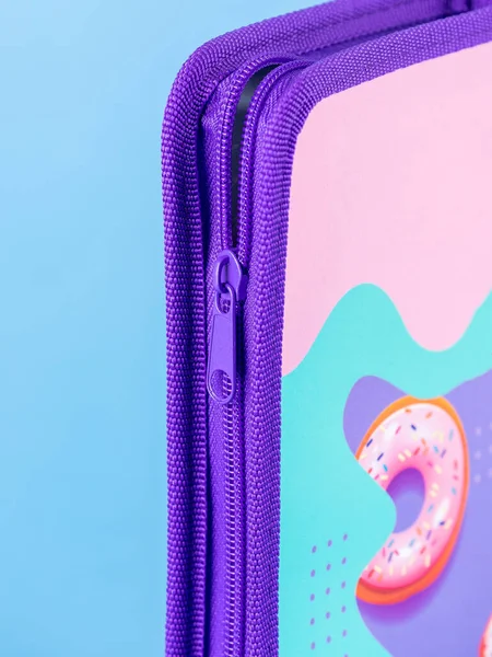 close-up of a zipper on a purple school pencil case on a blue background. Back to school. copy space