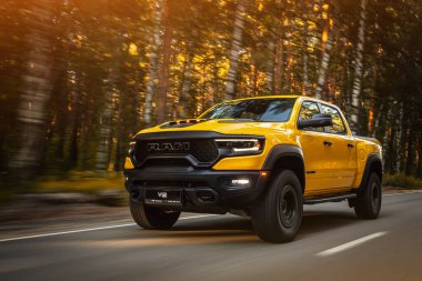  Novosibirsk, Rusya - 01 Haziran 2023: Sarı Dodge Ram Trx Havok versiyonu sıcak bir yaz gününde ormanın arka planına doğru sürüyor