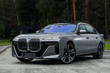  Novosibirsk, Rusya - 27 Temmuz 2023: Gümüş BMW 740 sıcak bir yaz günü, binanın arka planına karşı park etmiş.