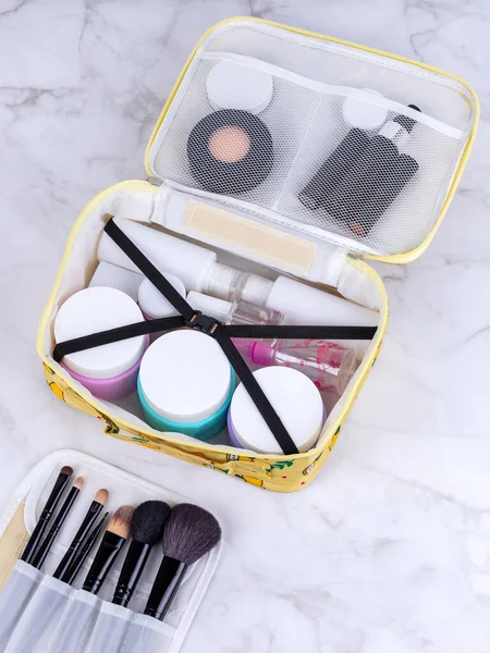 A beautiful yellow  cosmetic bag with the necessary products for the care of women's skin. Cosmetics, shampoo, creams, makeup brushes in a cosmetic bag against the backdrop of a beautiful women's room.