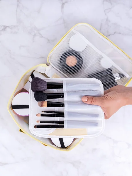 A beautiful white  cosmetic bag with the necessary products for the care of women's skin. Cosmetics, shampoo, creams, makeup brushes in a cosmetic bag against the backdrop of a beautiful women's room.