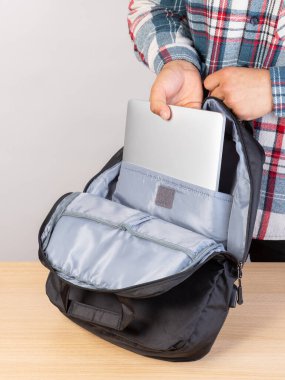 Genç bir erkek öğrencinin sırt çantasından dizüstü bilgisayar çıkarırken yakın plan fotoğrafı..