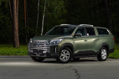 Novosibirsk, Rusya - 29 Ağustos 2023: yeşil SsangYong Rexton Khan, ön manzara. Muhteşem sonbahar kozalaklı ormanında park halindeki modern bir arabanın fotoğrafı.