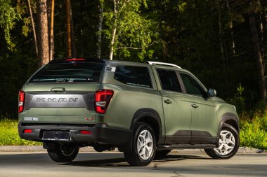 Novosibirsk, Rusya - 29 Ağustos 2023: yeşil SsangYong Rexton Khan, arka görüş. Muhteşem sonbahar kozalaklı ormanında park halindeki modern bir arabanın fotoğrafı.