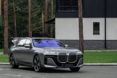 Novosibirsk, Rusya - 29 Ağustos 2023: BMW 7 Serisi, 740i, modern mimarinin arka planına karşı ön 3 / 4 görünüm 