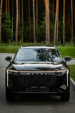 Novosibirsk, Rusya - 29 Ağustos 2023: siyah EXEED RX, modern mimarinin arka planına karşı ön görüş 
