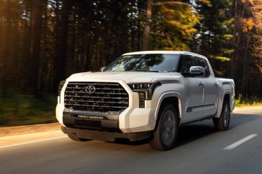 Novosibirsk, Rusya - Ekim 06, 2023: Beyaz Toyota Tundra, sıcak bir günde bir ormanın arka planına karşı araba sürüyor.