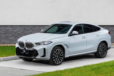 Novosibirsk, Rusya - 11 Ekim 2023: Sıcak bir yaz gününde beyaz BMW X6, binanın zeminine park etti. 