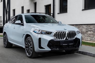  Novosibirsk, Rusya - 11 Ekim 2023: Beyaz BMW X6, sıcak bir sonbahar gününde binanın arka planına karşı sokağa park edilmiş. 