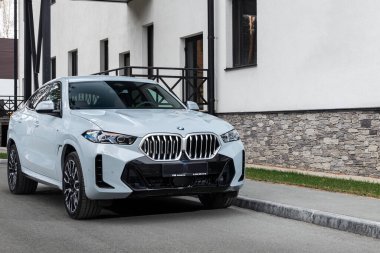  Novosibirsk, Rusya - 11 Ekim 2023: Beyaz BMW X6, sıcak bir sonbahar gününde binanın arka planına karşı sokağa park edilmiş. 