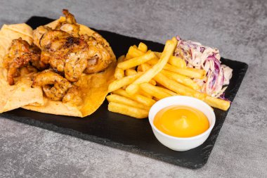 Sebzeli tavuk kebabı, lavaşlı patates kızartması ve sos.