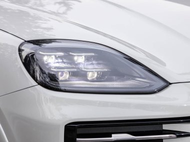 Novosibirsk, Rusya - 16 Kasım 2023: Beyaz Porsche Cayenne, dış görev. Modern araba ksenon lambasına yakın dur.