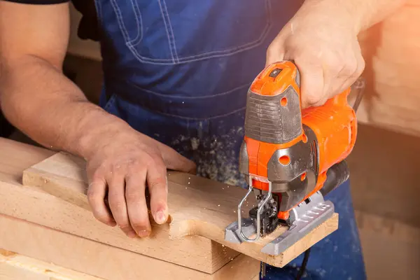 A carpenter using a jigsaw to cut wood cuts bars. Home repair concepts, close up.