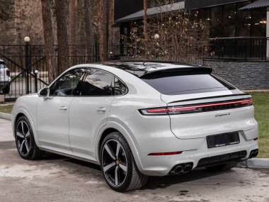 Novosibirsk, Rusya - 16 Kasım 2023: beyaz Porsche Cayenne, şehirde park edilmiş SUV, arka manzara