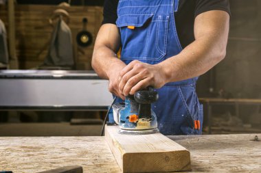 İş kıyafetleri konusunda deneyimli bir marangoz ve atölyede zımpara kağıdı kullanarak ahşap atölyesinde çalışan küçük bir büro sahibi.  