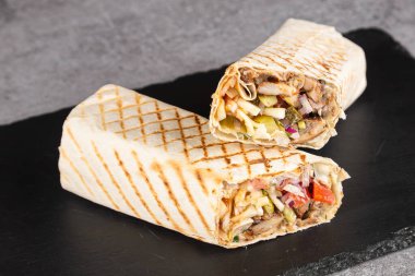 Burrito, arka planda bir kesme tahtasına tavuk ve sebzeyle sarılır. 