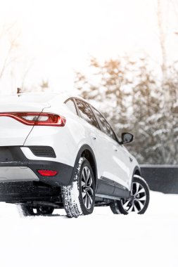 Modern bir sedan kış yolunun kenarına park edilmiştir. Kış karlı bir yolda bir arabanın yakın çekimi. Kayak merkezine aile seyahati konsepti.