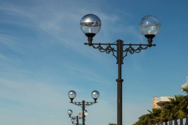 Gökyüzüne karşı kıvrımları ve kıvrımları olan güzel, klasik bir lamba direği. Sokakların ve parkların dekorasyonu. Şehirlerdeki ve kasabalardaki sokakların aydınlanması