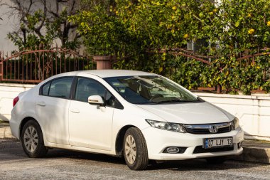 Taraf; Türkiye Şubat 04: 2024: Beyaz Honda Civiç, sıcak bir günde bir binanın arka planına, dükkanlara karşı sokağa park etti  
