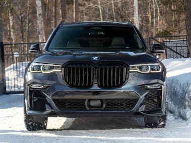 Novosibirsk, Rusya - 13 Mart 2024: BMW X7 şehir ve ormana karşı park edilmiş, ön manzara 