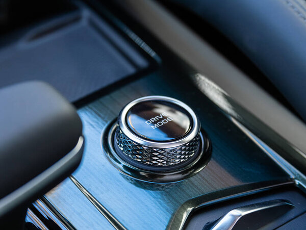 Novosibirsk, Russia - March  22 , 2024:  Geely; Monjaro , Close up  drive mode  button switches control for car with soft-focus and over light in the background.