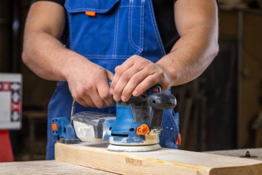 Bir rasgele yörünge sander atölye ile bir genç adam Oluşturucusu marangoz eşittir cilalar ahşap Yönetim Kurulu kapat