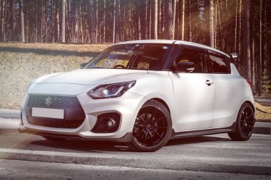 Novosibirsk, Rusya - 23 Nisan 2024: beyaz Suzuki Swift, ön manzara. Şehrin arka planında Japonya 'da yapılan özel hatchback.