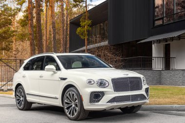 Novosibirsk, Rusya - 01 Mayıs 2024: Beyaz Bentley Bentayga, bir yaz günü caddeye park etmiş, binanın arka planına karşı,