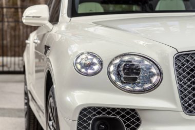 Novosibirsk, Rusya - 01 Mayıs 2024: Beyaz Bentley Bentayga, modern lüks bir arabanın far ışığı. Işıktan parlayan parlak cam araba farları.