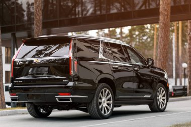 Novosibirsk, Russia -  April 30  , 2024:  black  Cadillac Escalade 600 ,  back   view. SUV   car  against city in  summer time  clipart