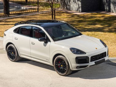 Novosibirsk, Rusya - 30 Nisan 2024: beyaz Porsche Cayenne, ön manzara. Yaz zamanı şehre karşı SUV arabası 