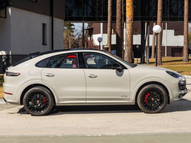 Novosibirsk, Rusya - 30 Nisan 2024: beyaz Porsche Cayenne, yan görüş. Yaz zamanı şehre karşı SUV arabası 