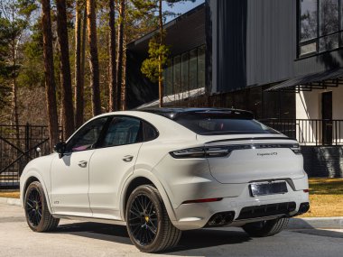 Novosibirsk, Rusya - 30 Nisan 2024: Beyaz Porsche Cayenne bir yaz günü parkın arka planına park etti