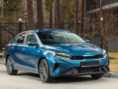 Novosibirsk, Rusya - 30 Nisan 2024: Kia K3, cephe manzaralı. Yaz zamanı Sedan araba parka karşı. 