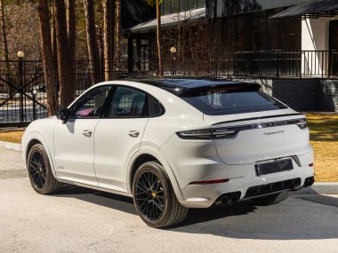Novosibirsk, Rusya - 30 Nisan 2024: beyaz Porsche Cayenne bir şehrin parkı. Başka araba ve insan yok.. 